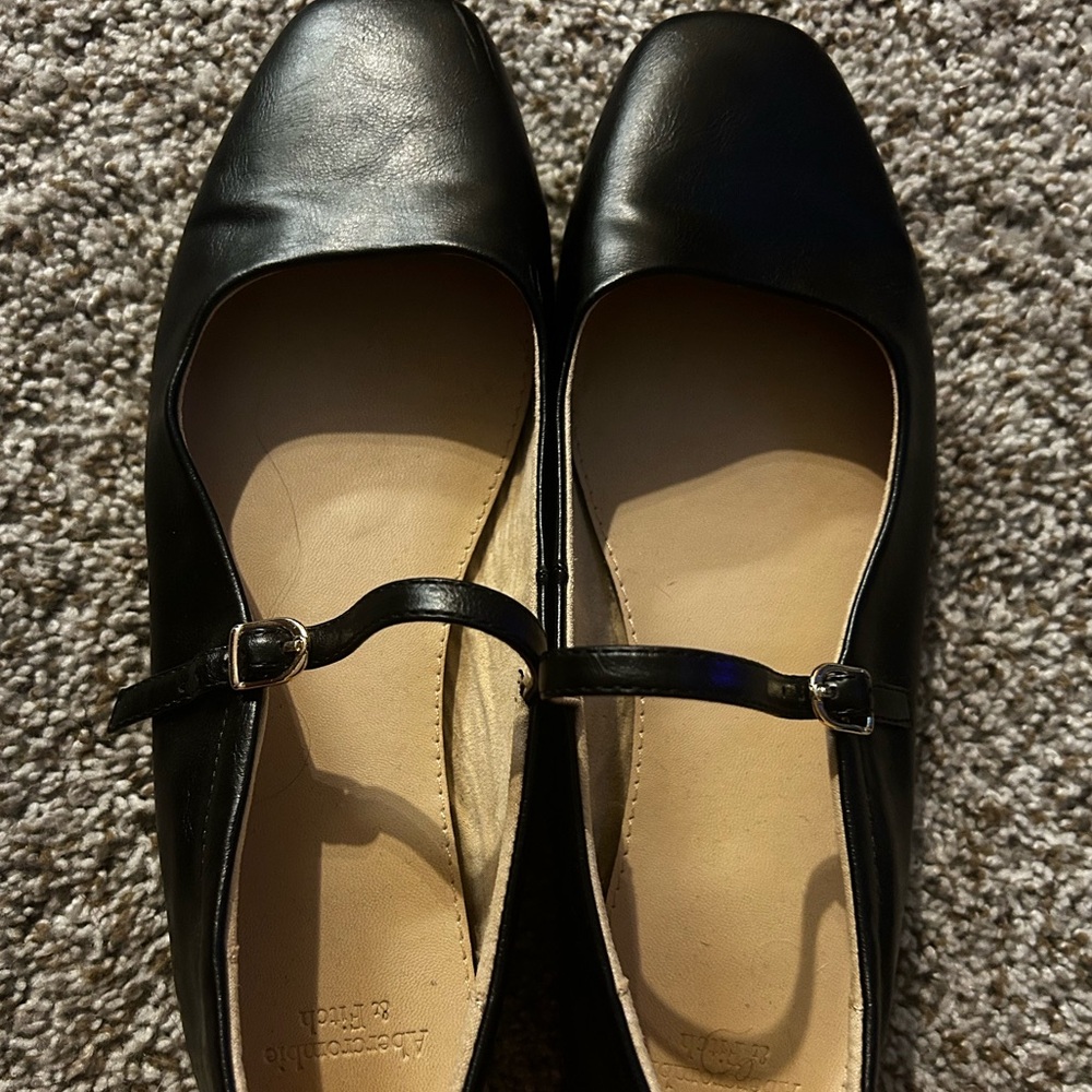 black ballet flat with a square toe and strap with a gold buckle
